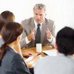 A stern senior executive explaining something to his team in a meeting